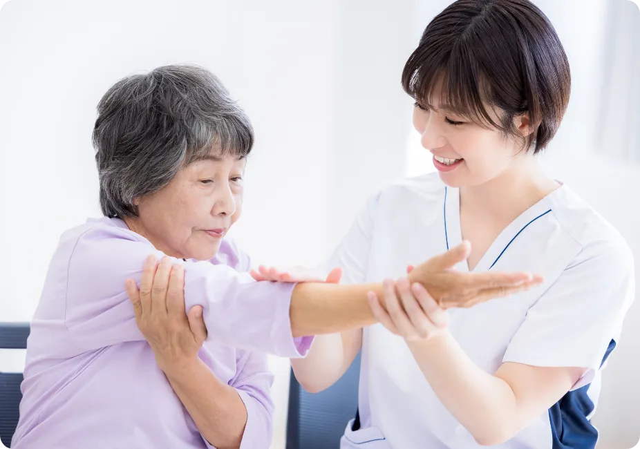 腕のリハビリを行う高齢女性とスタッフ